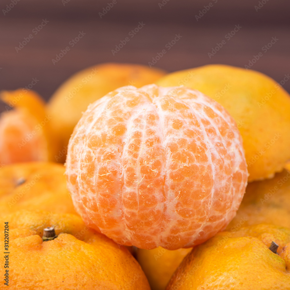 新鲜、美丽的橙色橘子放在深色木桌上的竹筛上。时令、传统
