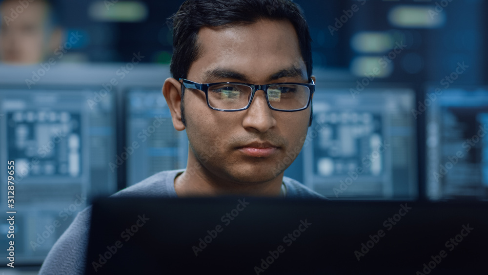 一位聪明英俊的IT专家在个人电脑上工作的肖像。背景博克