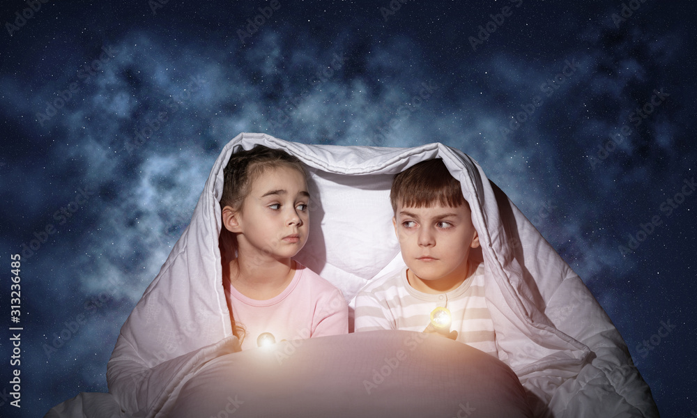 Children with flashlights in bed