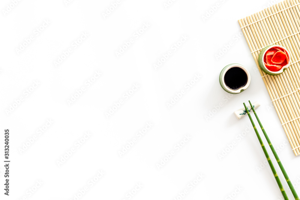 餐桌上有寿司。筷子，小碗里有生姜和炒菜，垫子放在白背上