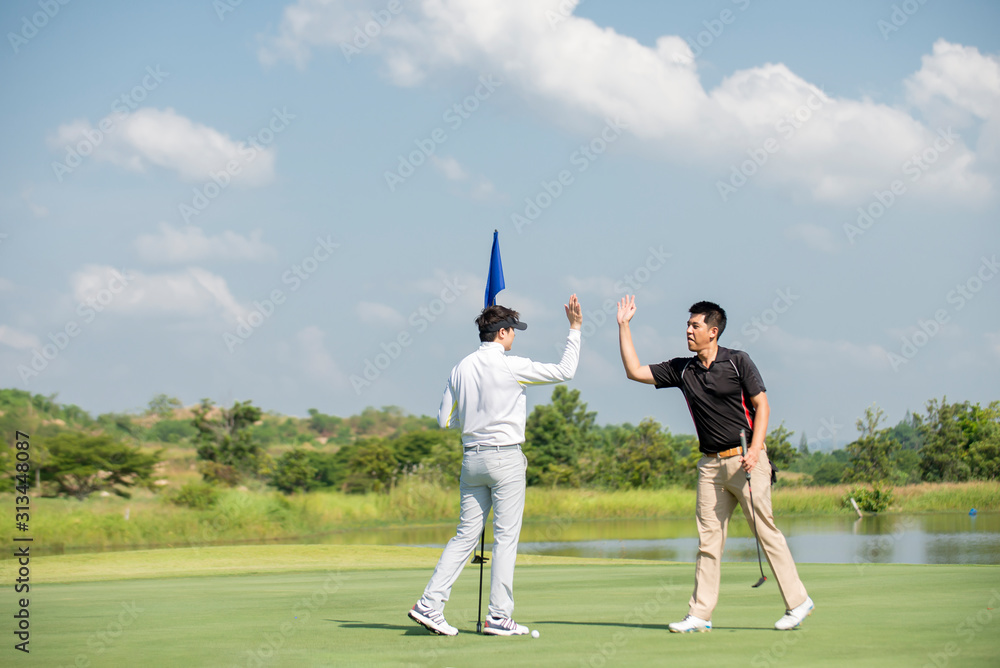 两名亚洲男子高尔夫球手在高尔夫球场击掌