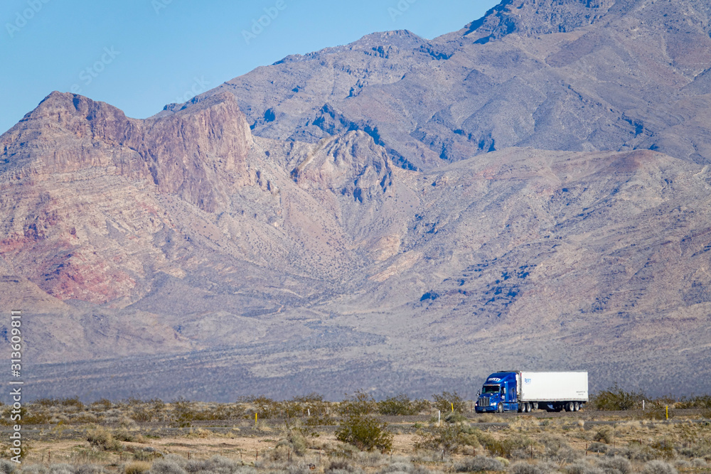 闪亮的蓝色18轮车穿过犹他州沙漠深处的贫瘠景观。