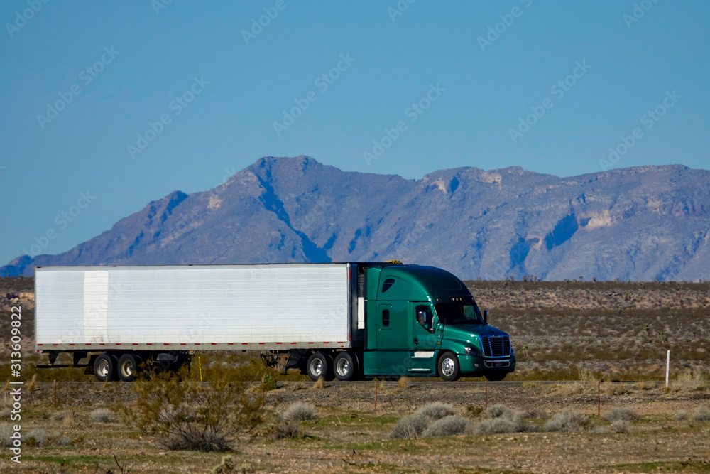 特写：一辆绿色半挂卡车周围贫瘠景观的酷镜头。
