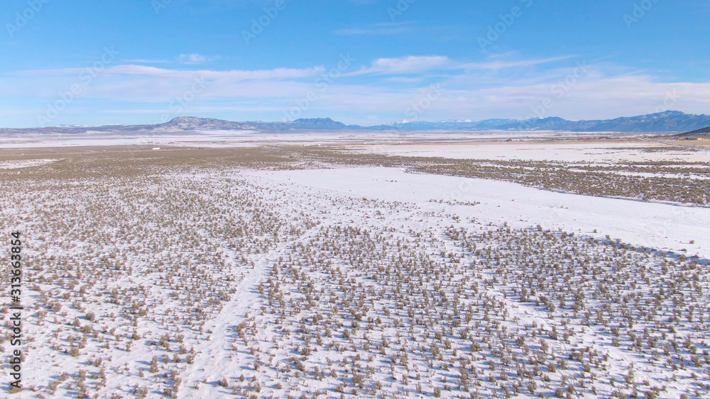 空中飞行：飞越犹他州的雪原，飞向远处的高速公路。