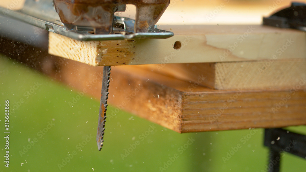 MACRO:竖锯刀片切割成坐在木匠工作台上的胶合板