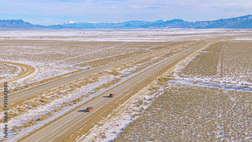 无人机：沿着沥青公路飞行，带领车辆穿越白雪皑皑的沙漠。