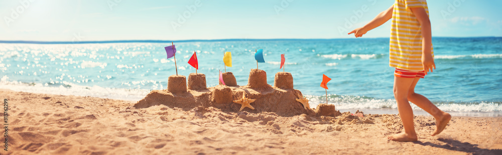男孩夏天在海滩上建造沙堡
