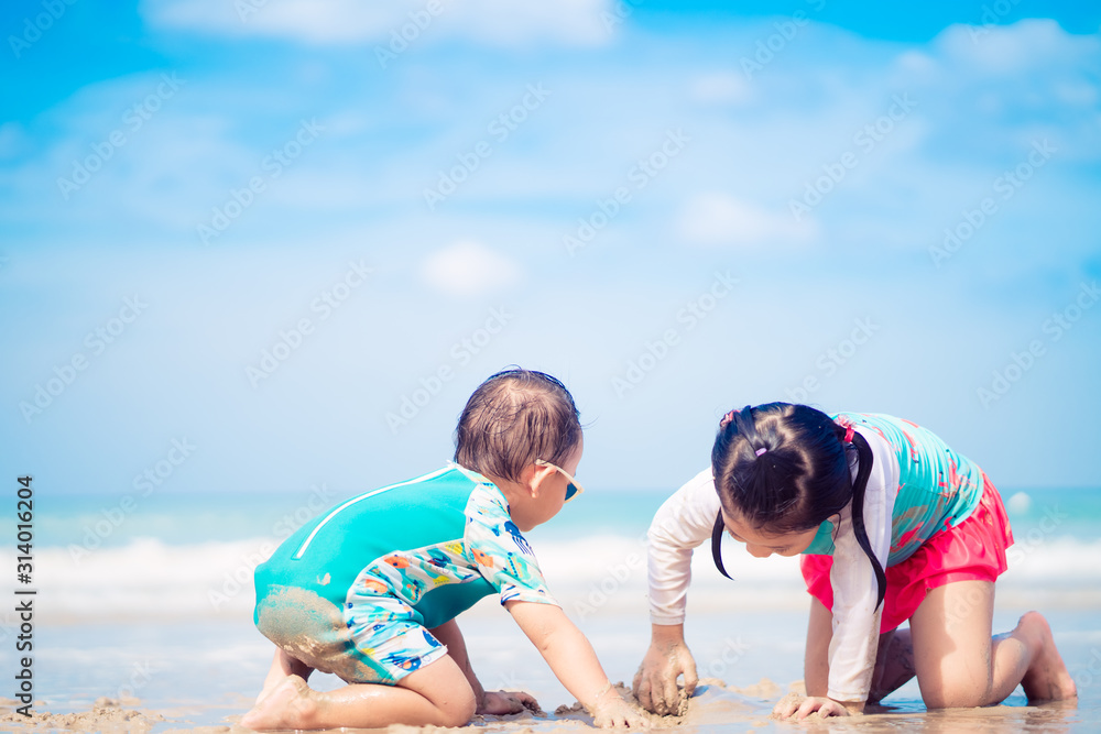 5.10岁的亚洲小女孩和她2.9岁的小弟弟在海滩上玩耍。家人在一起