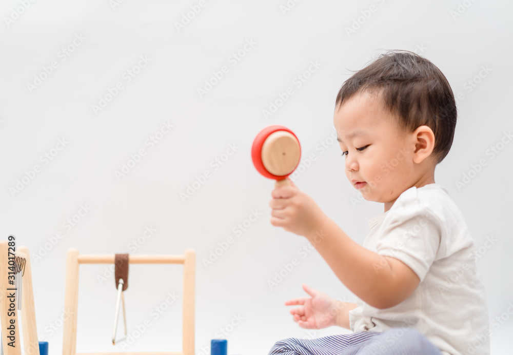 Little baby drummer boy playing percussion and hitting the drum set at home.Asian boy playing and si