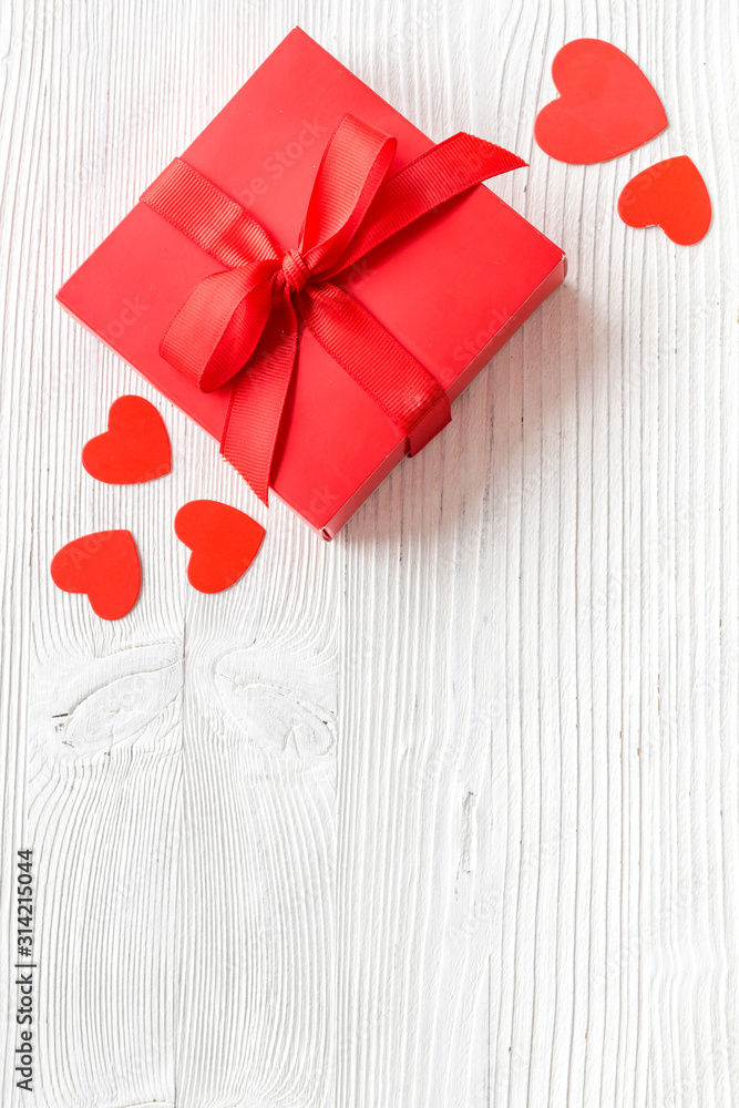 情人节送给爱人的礼物。白色木质背景顶部靠近心形的红色礼物盒-
