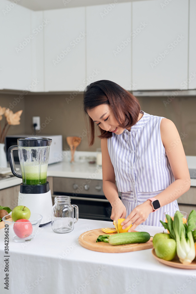女人在家厨房切蔬菜做奶昔。健康的概念。