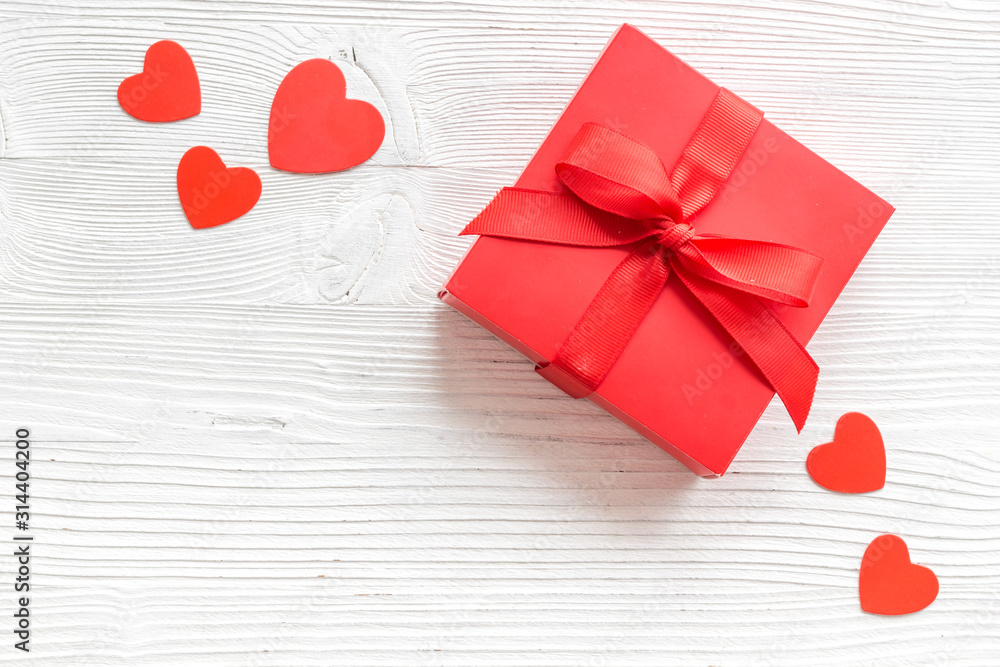 情人节送给爱人的礼物。白色木质背景顶部靠近心形的红色礼品盒-