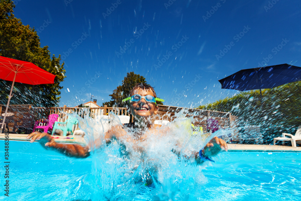 Boy splash jumping into the pool wearing googles