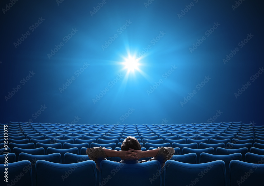 空荡荡的蓝色电影院，贵宾坐在中央，看着明亮的屏幕。混合媒体。