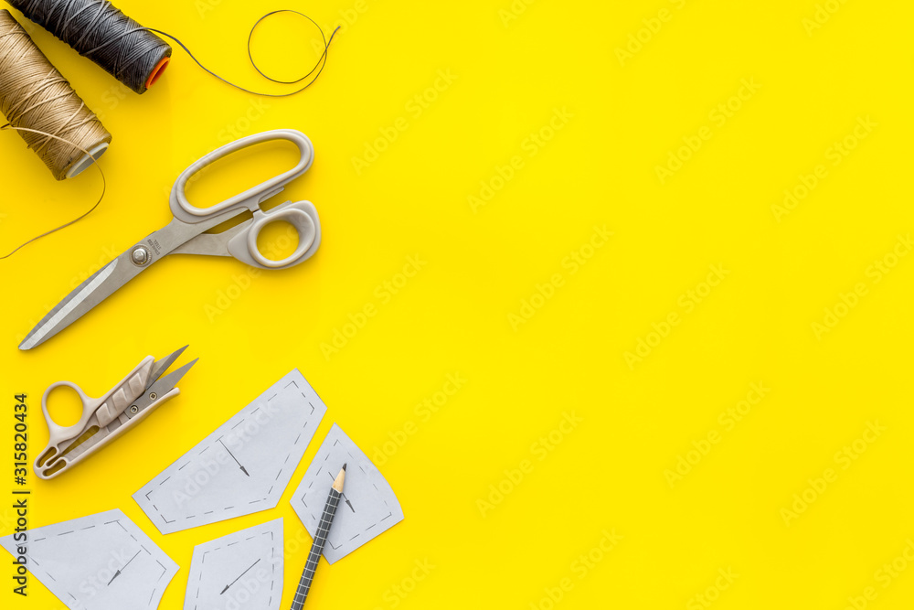 服装设计师工作台。黄色背景上的图案、剪刀、线自上而下的复制空间