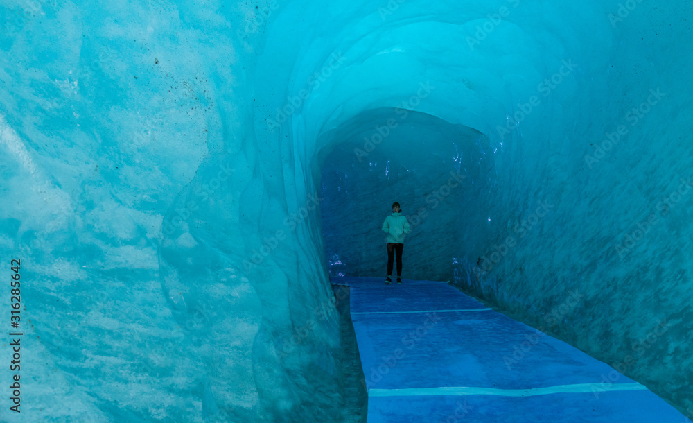 一名年轻女子在通往法国融化冰川的结冰走廊上摆姿势
