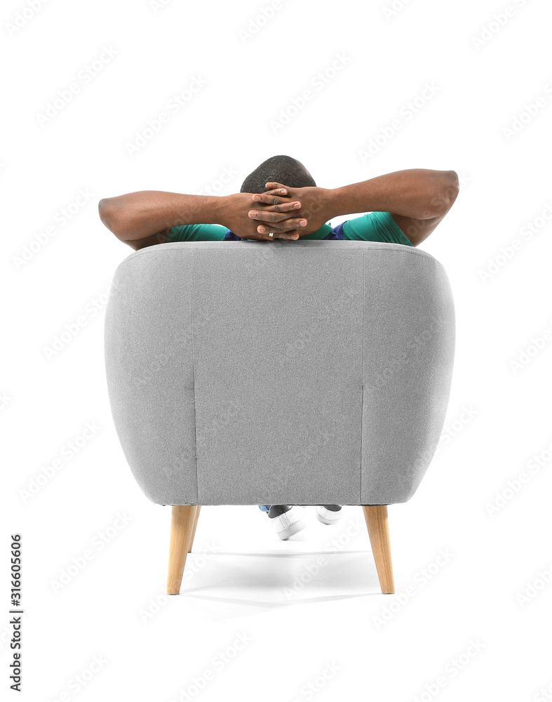 一名非裔美国男子在扶手椅上放松，背景为白色，后视