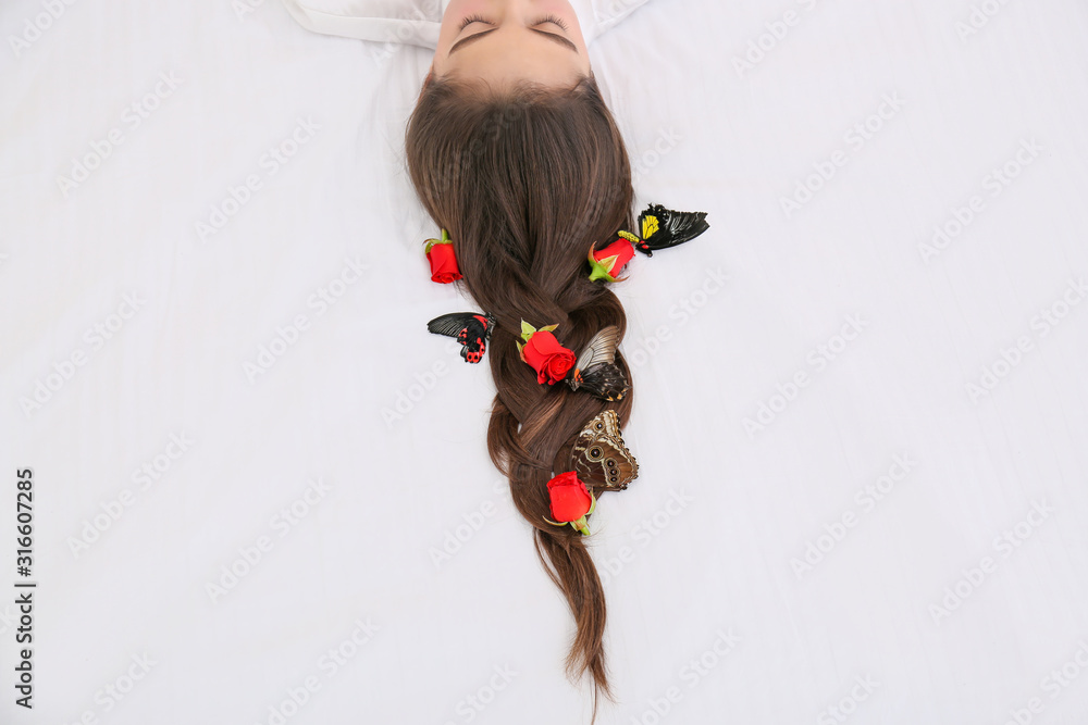 美丽的年轻女子，头发上有花和蝴蝶，躺在床上