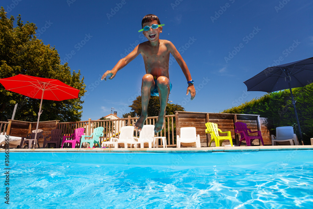 快乐尖叫的小男孩孩子在游泳池半空中跳跃的肖像