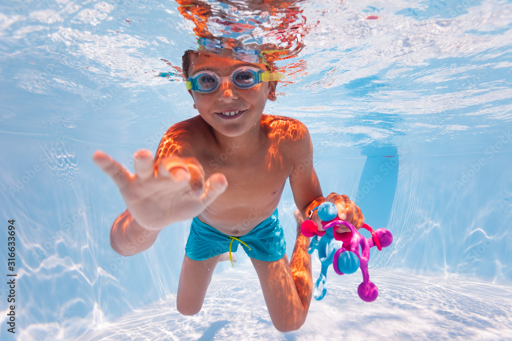 小孩在水下游泳，戴着谷歌眼镜在游泳池里收集玩具，做有趣的游泳运动