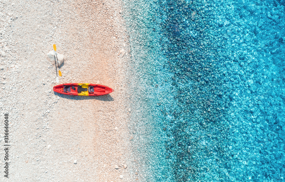 红色独木舟俯瞰空旷的沙滩，阳光明媚的双桅帆船俯瞰透明的蓝色海水