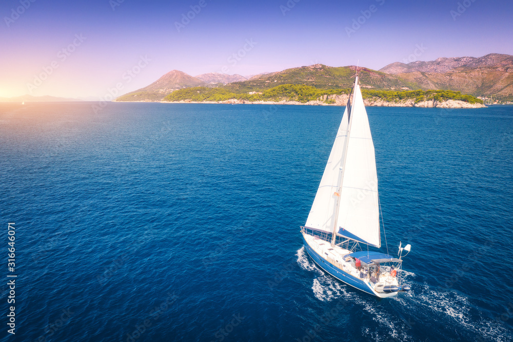 阳光明媚的夏日傍晚，美丽的白色帆船在蔚蓝的大海中鸟瞰。亚得里亚海
