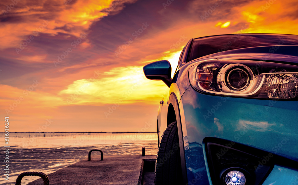 日落时分，运动时尚的蓝色紧凑型SUV停在海边的水泥路上