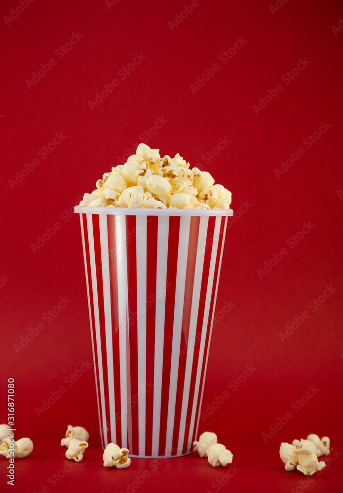 红色爆米花杯里的黄油爆米花，红底上的房子或电影院里的零食