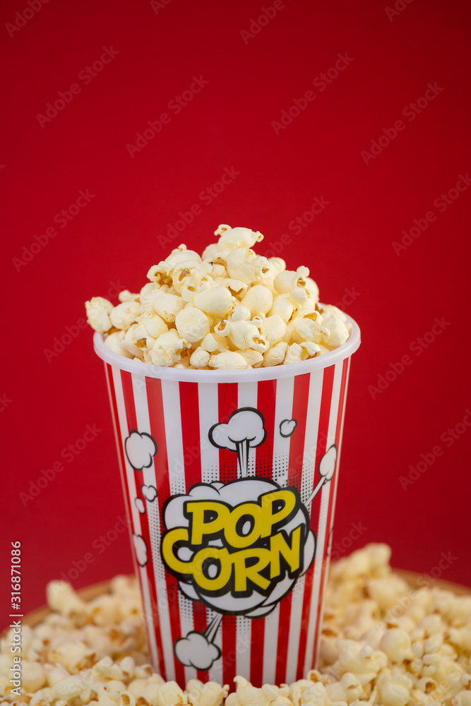 红色爆米花杯里的黄油爆米花，红底上的房子或电影院里的零食