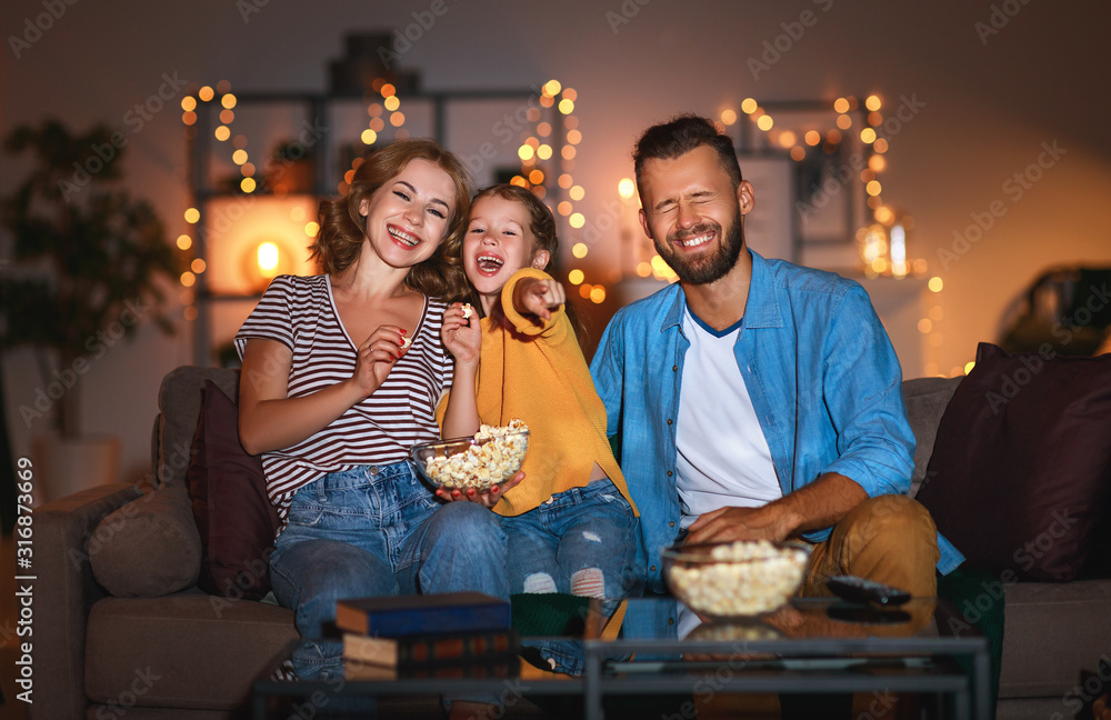 家庭母亲父亲和孩子女儿在晚上用爆米花看投影仪、电视、电影a