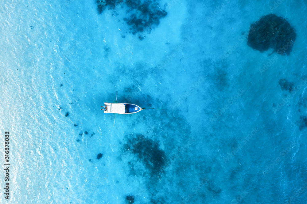 夏日日落时，白色小船在清澈的蓝色水中的鸟瞰图。ya的无人机俯视图