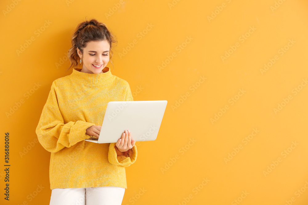 穿着保暖毛衣，背景是笔记本电脑的漂亮年轻女人