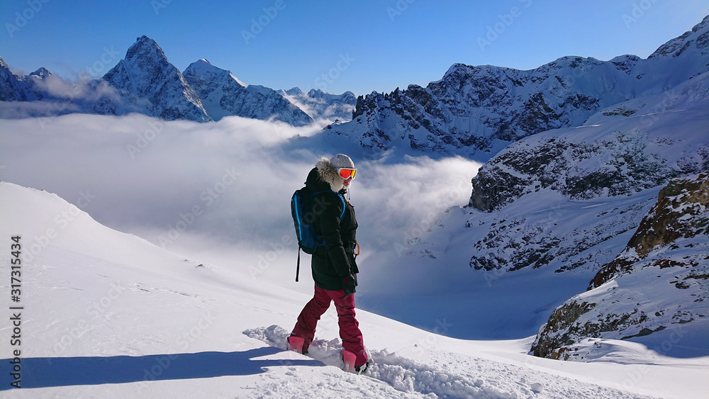 Cheerful female snowboarder poses on the snowy mountaintop before her descent