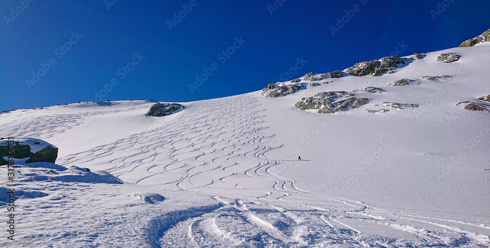 孤独的游客滑下一个没有房间的斜坡，斜坡上布满了滑雪板和滑雪板。