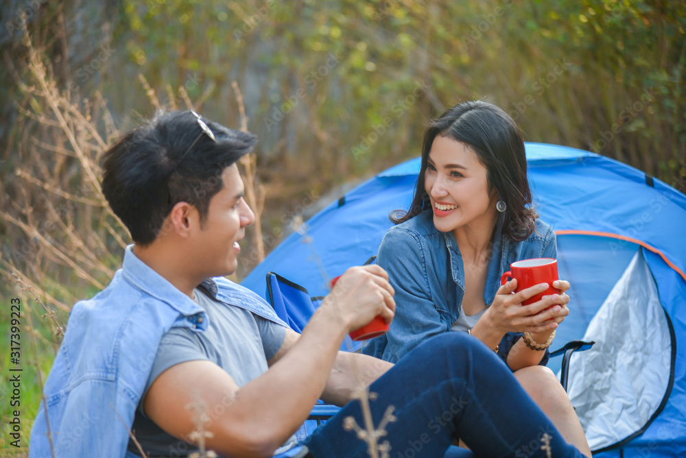 美丽的亚洲女人在白色帐篷露营前喝咖啡并与男友交谈