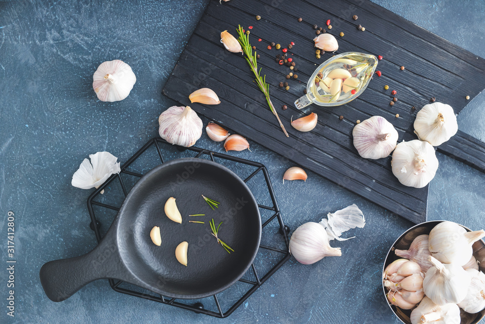 Fresh garlic with oil, spices and herbs on dark background