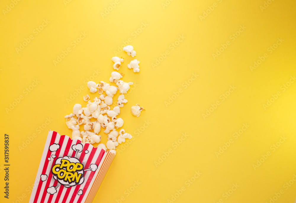 红色爆米花杯里的黄油爆米花，黄色背景的房子或电影院里的零食