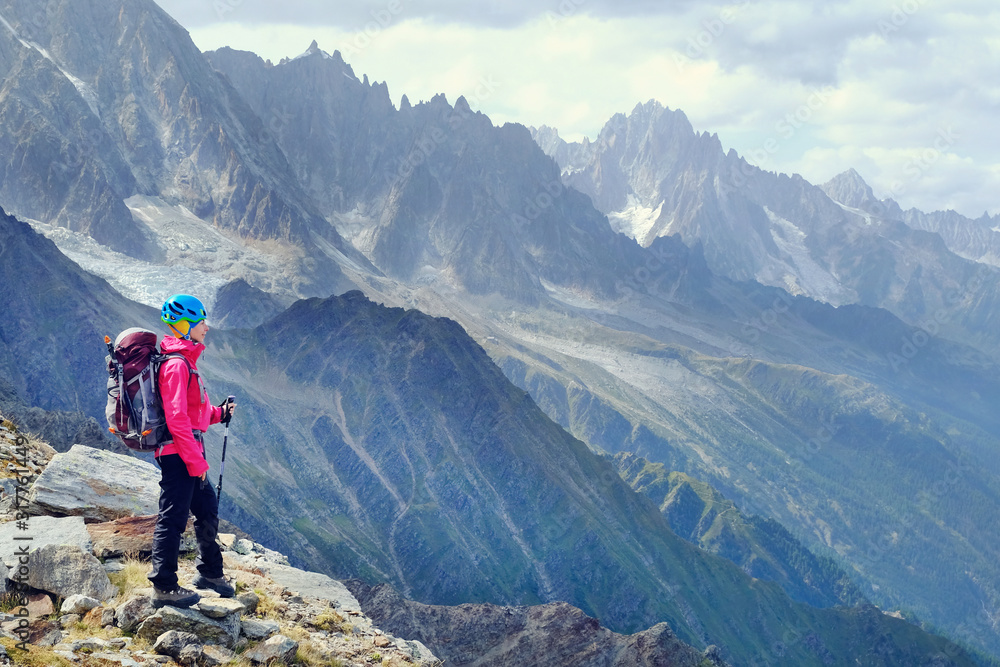 背着背包徒步旅行的女人在山顶放松，欣赏山谷的景色