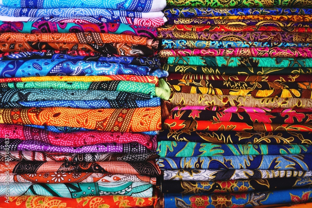 Piles of colorful printed fabric for sale at an outdoor market in Bali, Indonesia