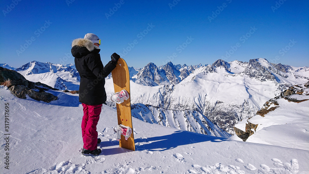 不可识别的单板滑雪运动员俯瞰白雪皑皑的山谷和令人惊叹的落基山脉