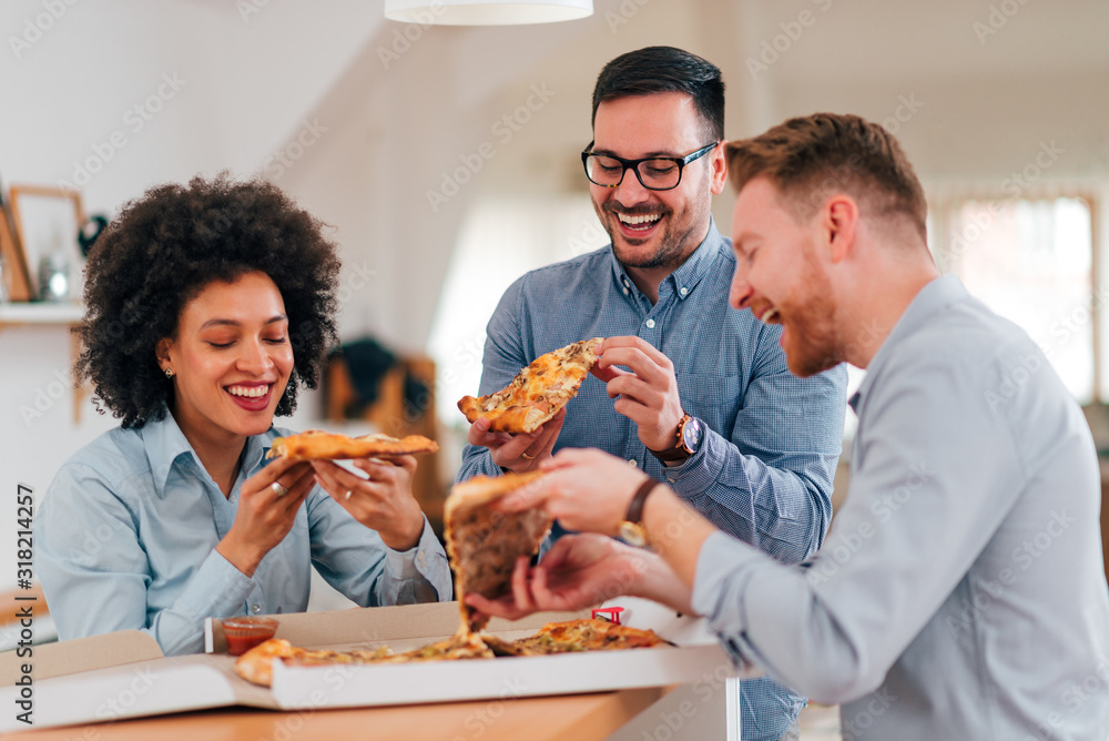 一群微笑的人在休息时吃披萨。