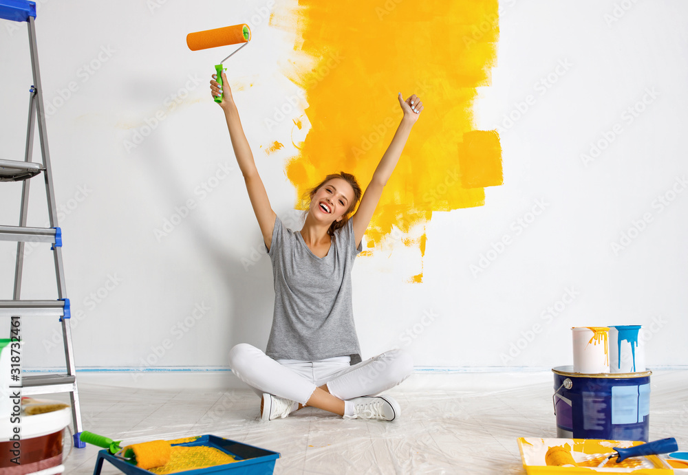 公寓里的维修。快乐的年轻女人粉刷墙壁。