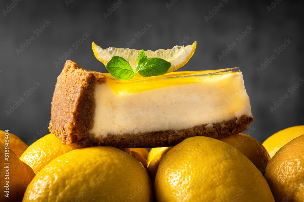 新鲜薄荷叶柠檬芝士蛋糕片放在灰色背景的黄色成熟柠檬上。Be