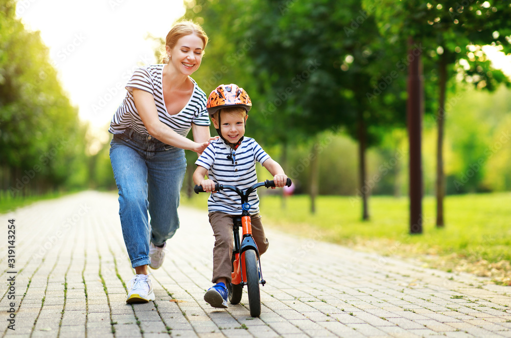 幸福的家庭母亲教孩子儿子在公园里骑自行车
