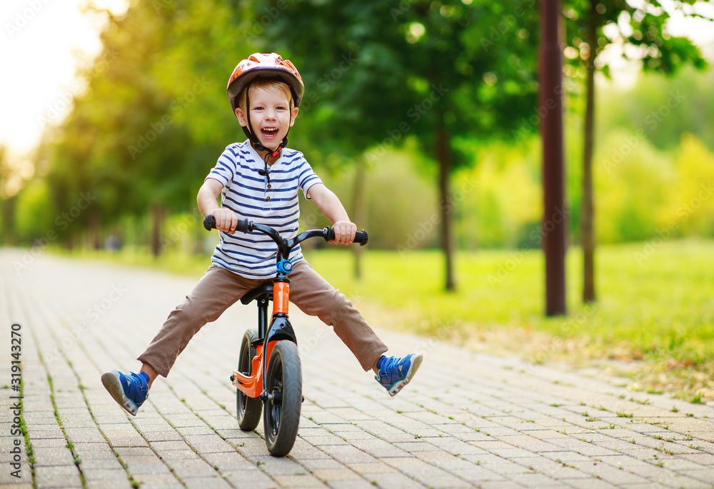 快乐的小男孩夏天在公园的跑道上骑行