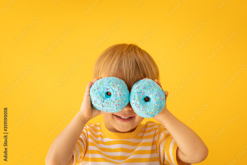 快乐的孩子拿着上釉的甜甜圈