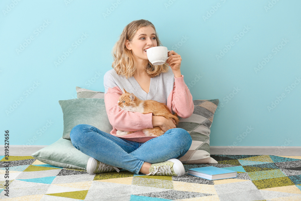 美丽的年轻女人带着可爱的猫在家喝茶