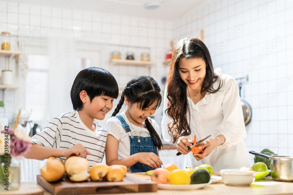可爱可爱的亚洲家庭在家的厨房里做食物。微笑的母亲和孩子的肖像sta
