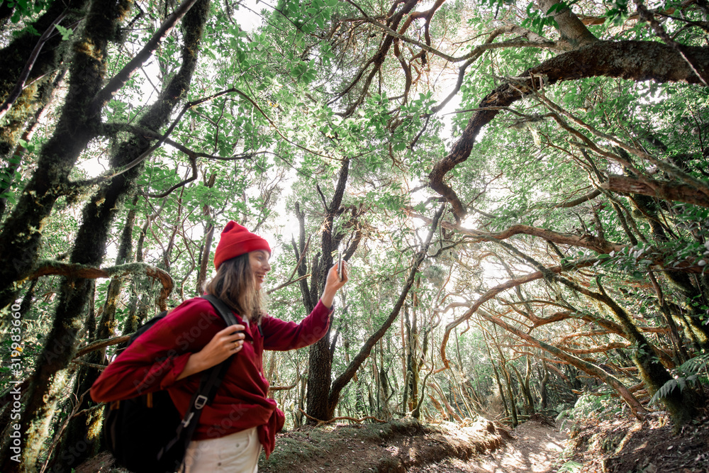 穿着红帽子和衬衫的年轻女子在美丽的雨林中旅行，拍摄陆地景观