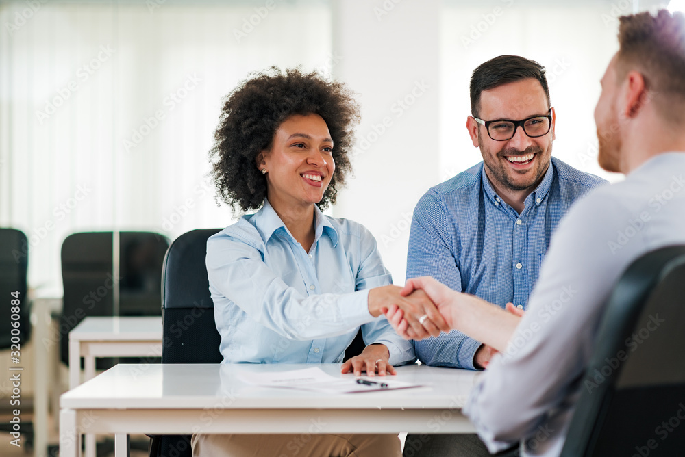 微笑的人力资源经理与求职者握手。